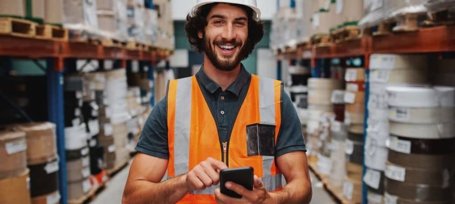 Male warehouse worker using smartphone.