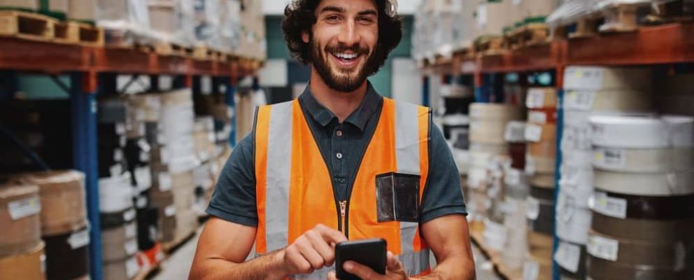 Male warehouse worker using smartphone.